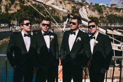 Dapper Groomsmen in Black Tuxes and Sunglasses | Vitaly M Photography | Black Tie Coastal Wedding with Classic Beach Details