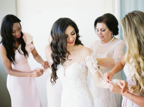 Bridesmaids Helping the Bride Put on her Wedding Dress