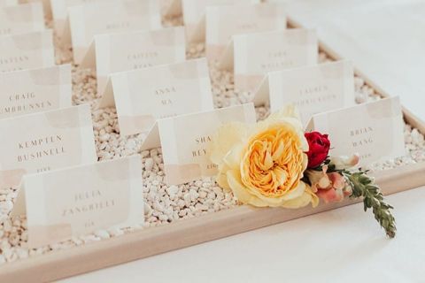 Minimalist White Seating Chart with Escort Cards on a Bed of Pebbles