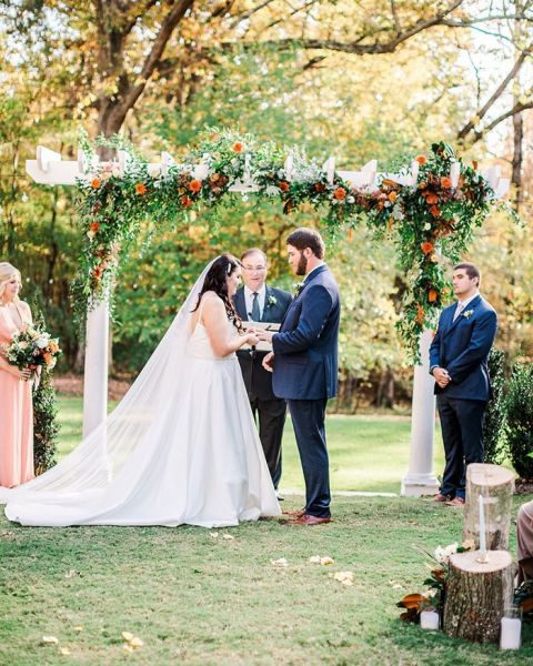 Outdoor Wedding Ceremony with an Arch of Flowers in the Perfect Colors for a Fall Wedding
