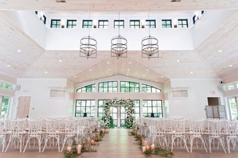 White barn wedding venue with candle lantern aisle decor
